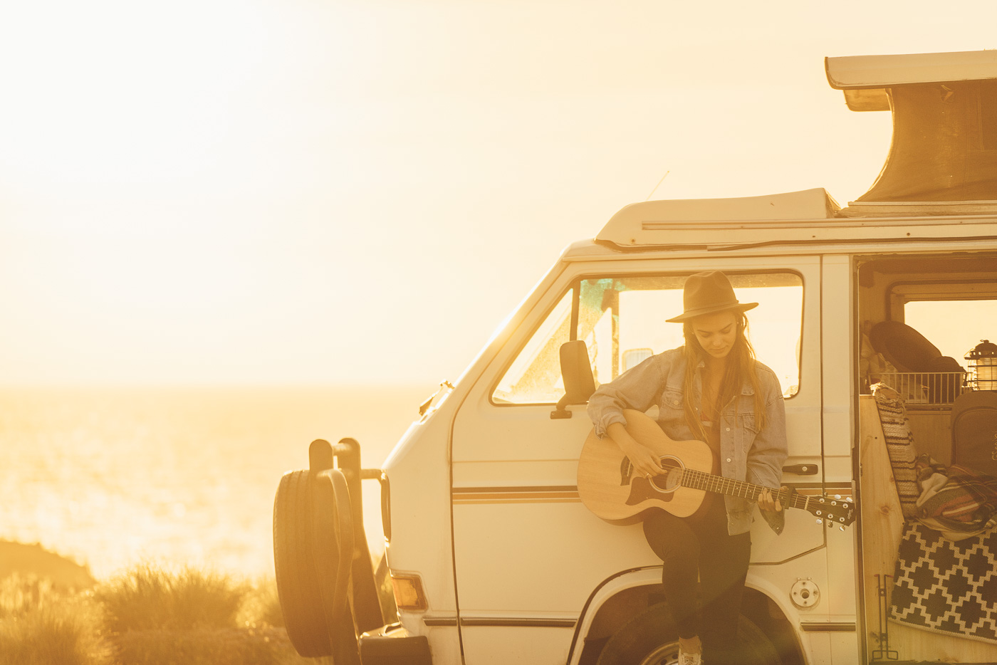 Tristyn Lecia playing guitar in the sunset from the front of the Will and Bear Volkswagen van. Photo by Sony Ambassador Stefan Haworth