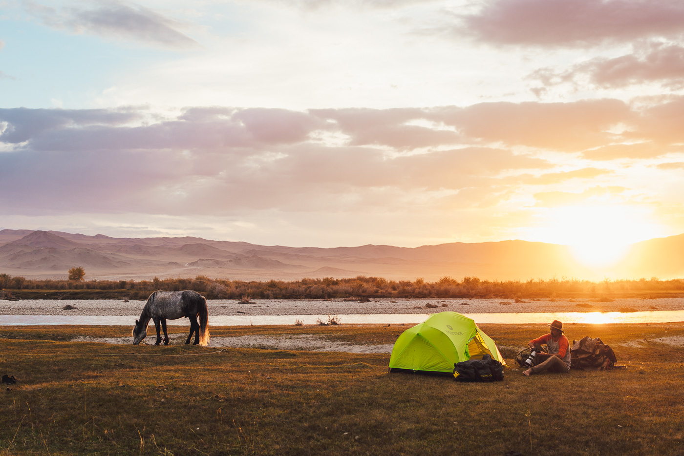 Solo horse trekking trip through Mongolia, Stefan Haworth looking through images at the campsite at sunset