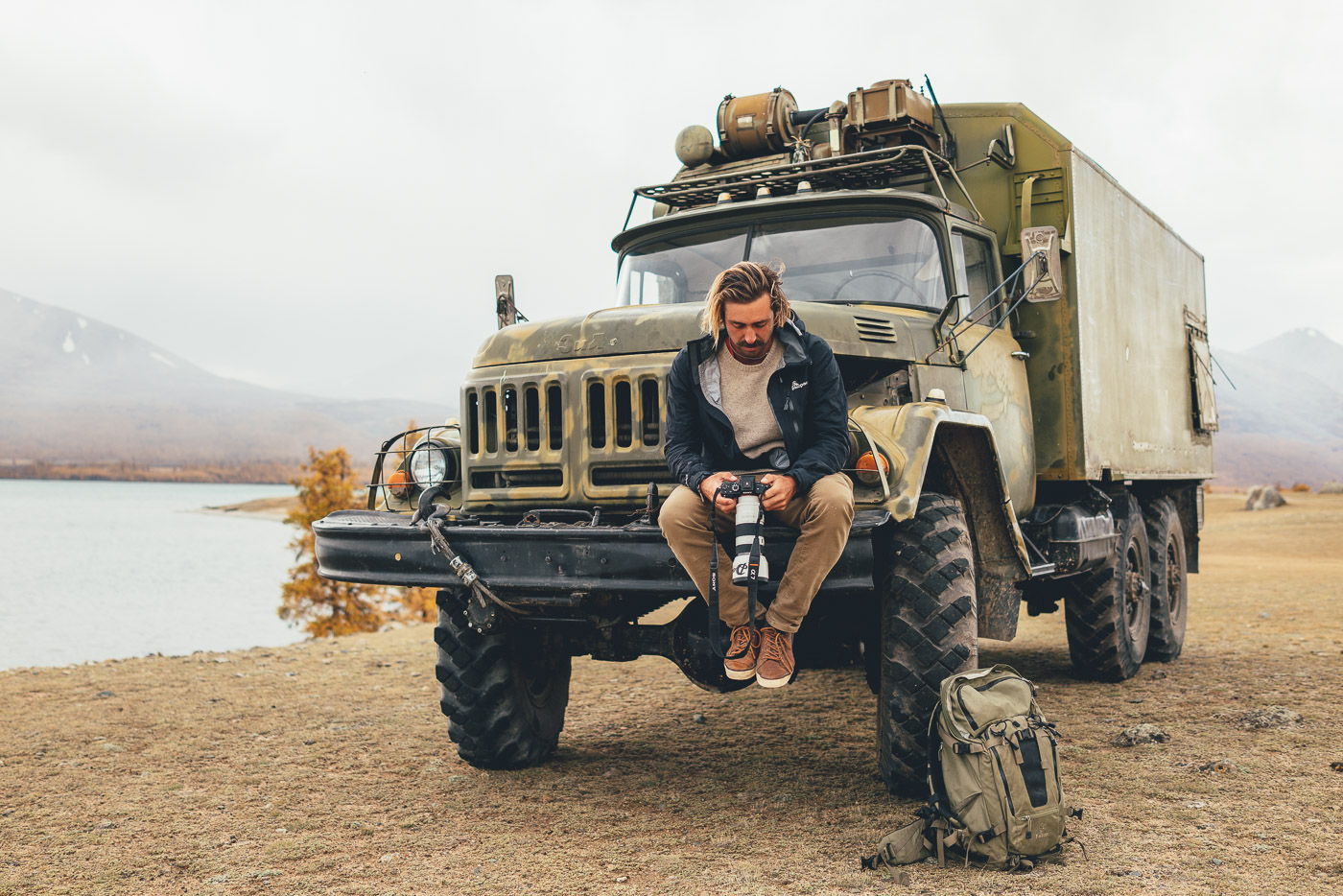 Stefan Haworth sitting on army truck and reviewing images in Mongolia with Sony a7rII and FE 70-200mm f/4 G OSS