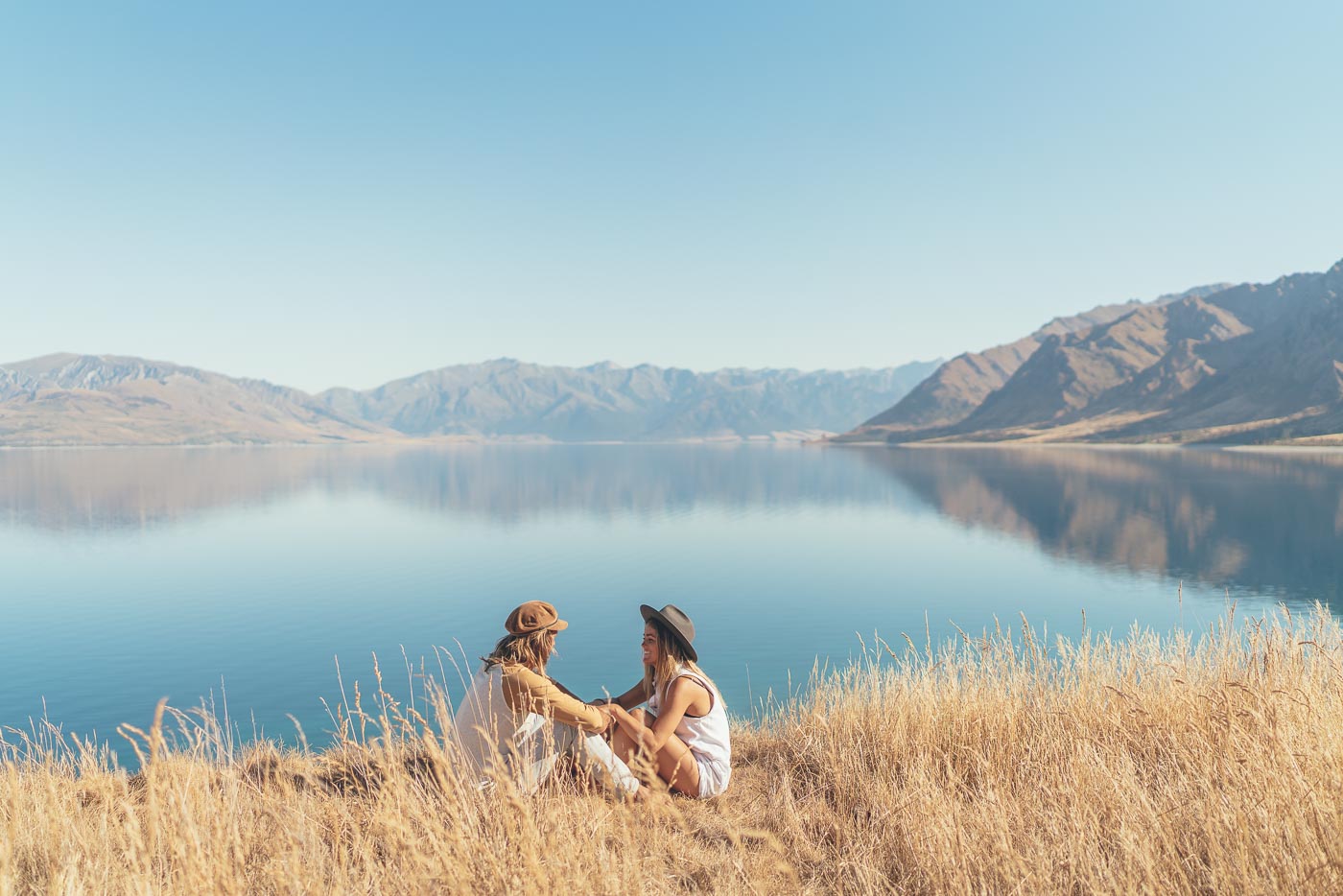 Photographer Stefan Haworth and Jess Davis sitting on the bank of Lake Hawea in New Zealand on the Will and Bear Road trip