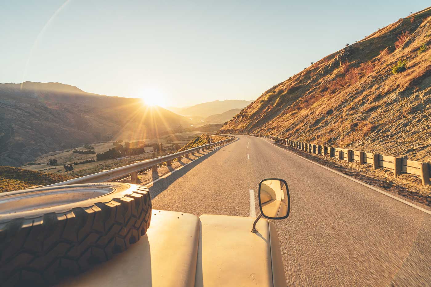 Land Rover driving over crown range at sunset in New Zealand