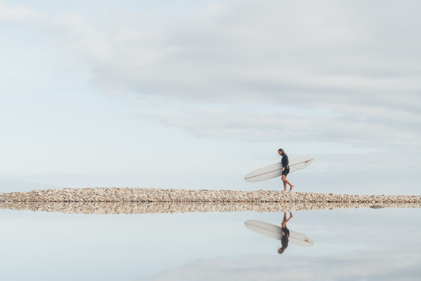 Reflection of Surfer carrying Surfboard to the beach in New Zealand