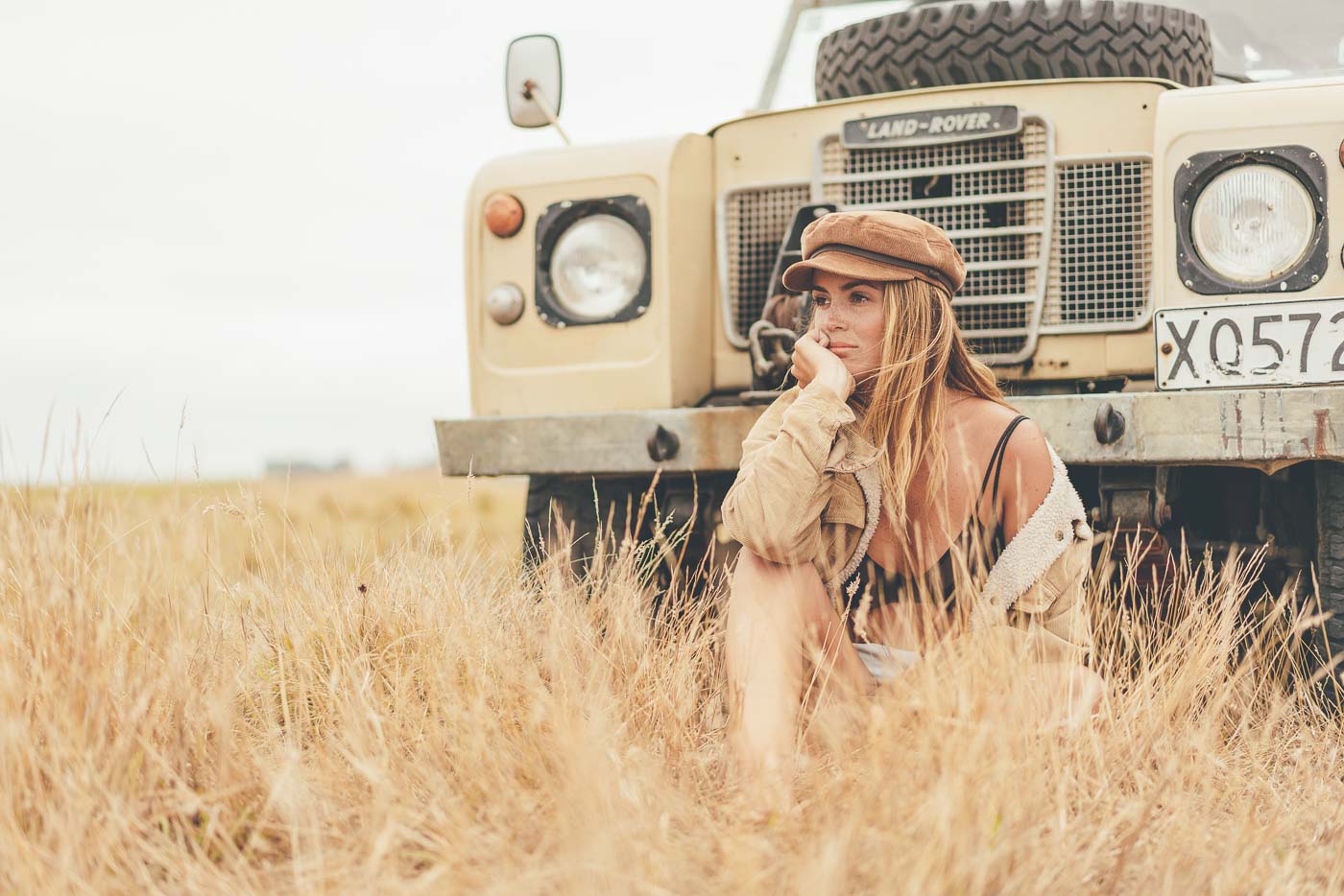 Jess Davis sitting in long grass in front of land rover