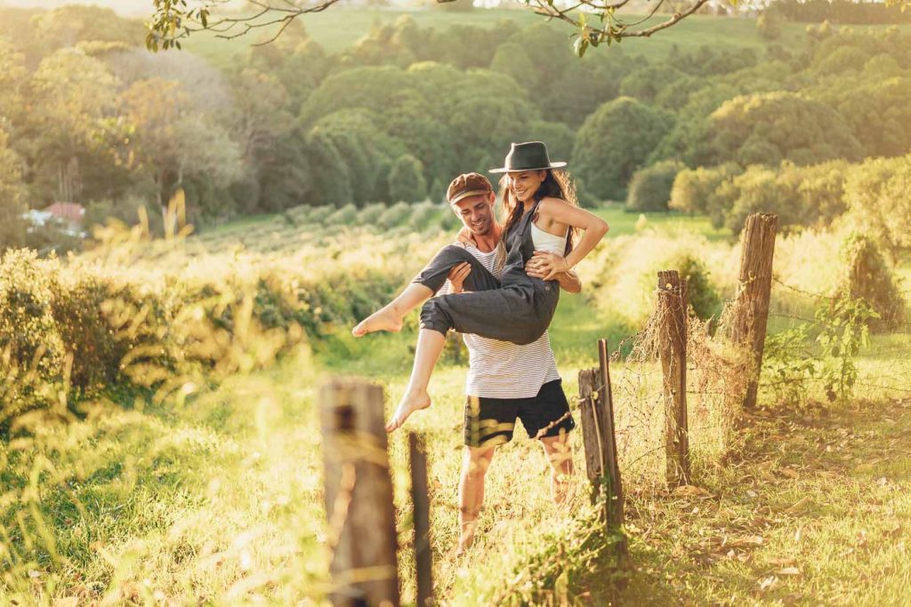 guy lifting girl over a fence at sunset