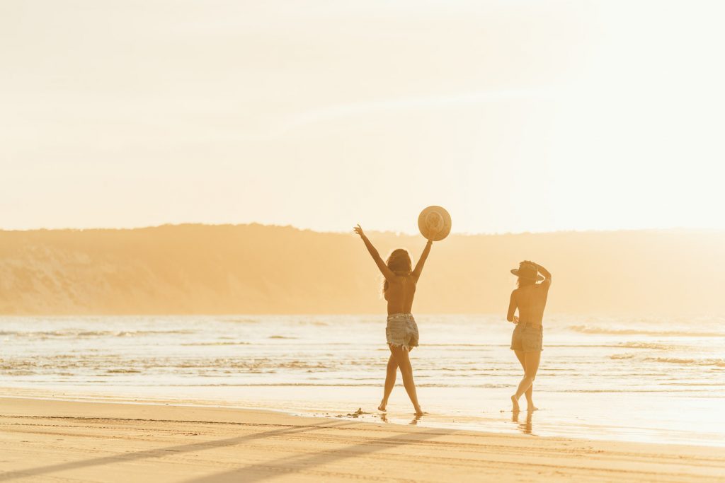 Girls running topless at the beach at sunset