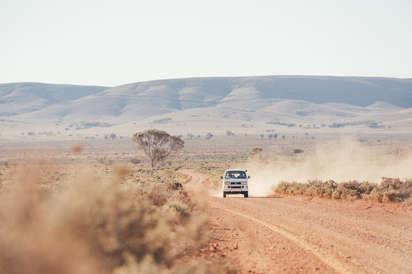 Volkswagen Campervan driving down long dusty road in South Australia with Will and Bear. Captured by Adventure Photographer Stefan Haworth