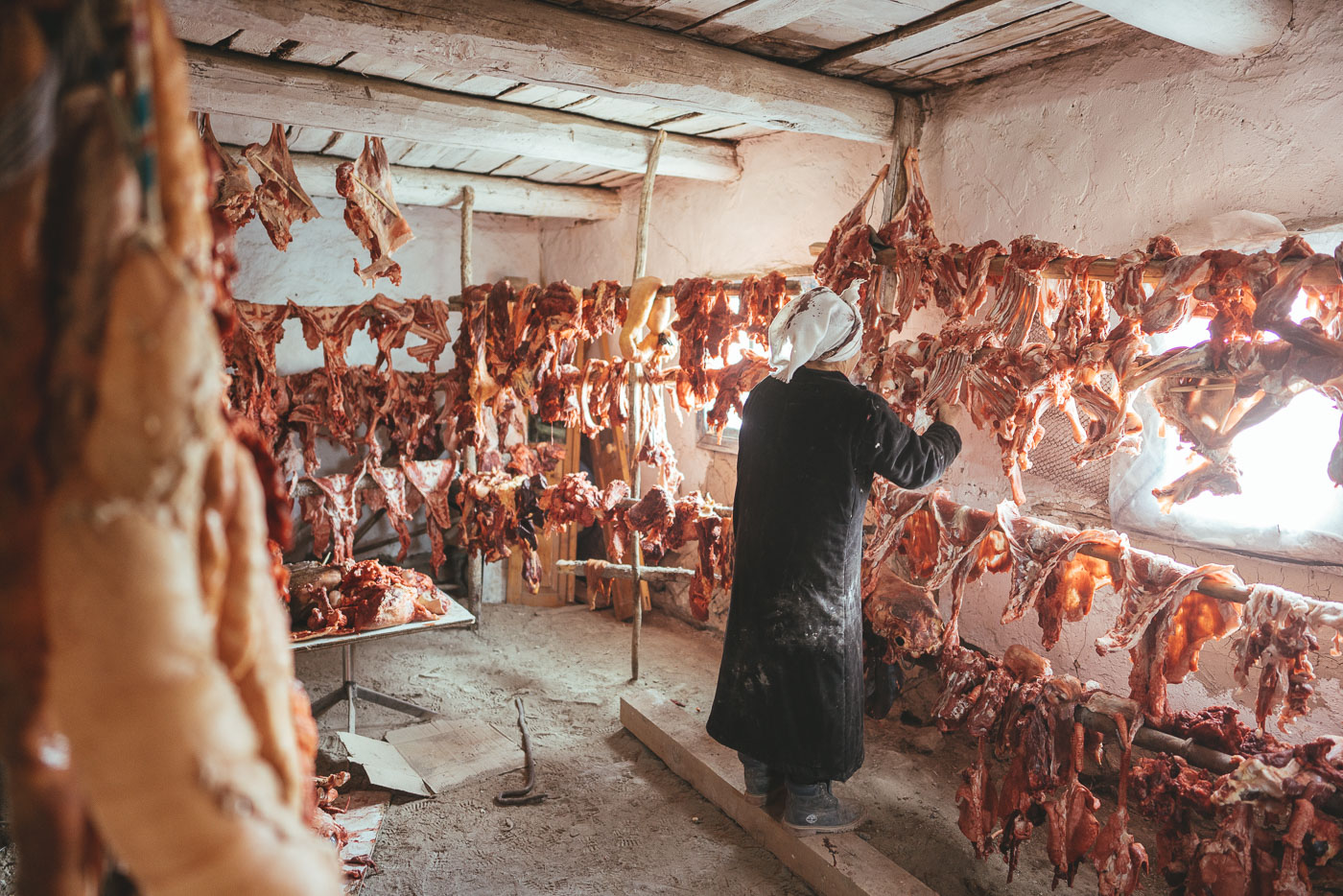 Mongolian mother hanging meat from the winter slaughter in the storage room in Mongolia. Captured by adventure photographer Stefan Haworth