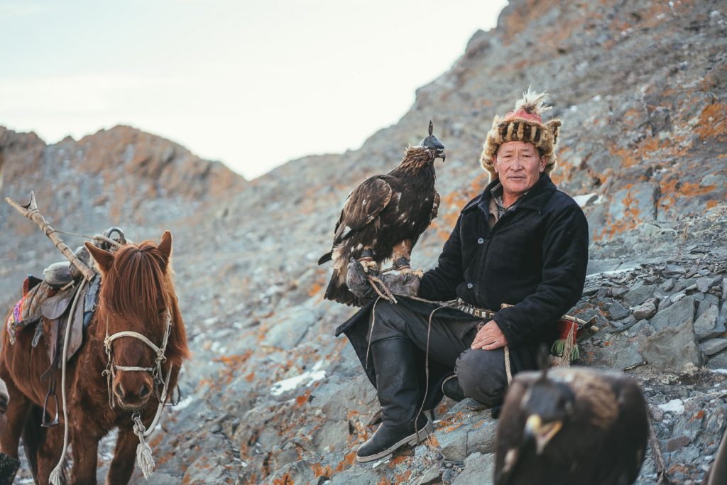 Kazakh eagle hunter resting on the rocks with eagle in hand. Captured by Sony ambassador and Adventure photographer Stefan Haworth