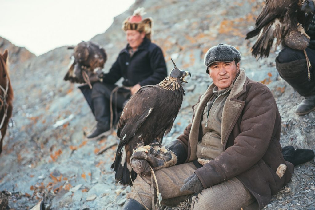 Kazakh eagle hunter resting on the rocks with eagle in hand. Captured by Sony ambassador and Adventure photographer Stefan Haworth