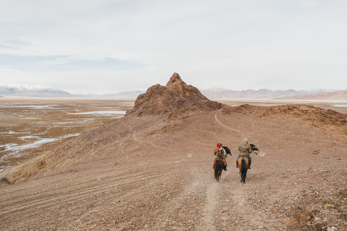 Two Kazakh Eagle Hunters on horseback riding through the mountains of western Mongolia. Captured by adventure photographer Stefan Haworth