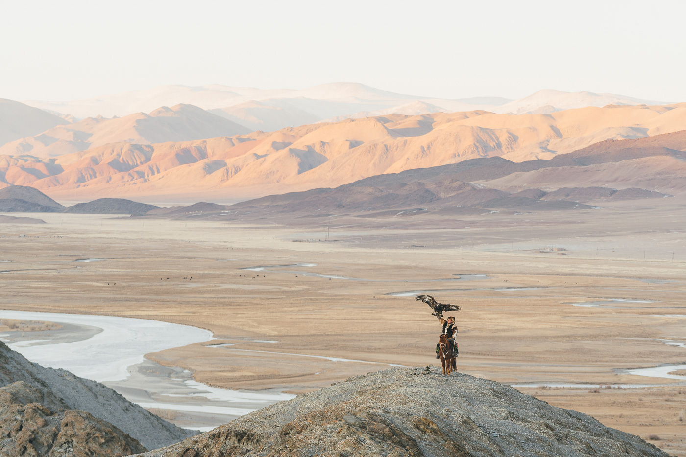 Kazakh eagle hunter releasing the eagle on top of a mountain at sunset in Western Mongolia. Photographed by adventure photographer and Sony ambassador stefan Haworth