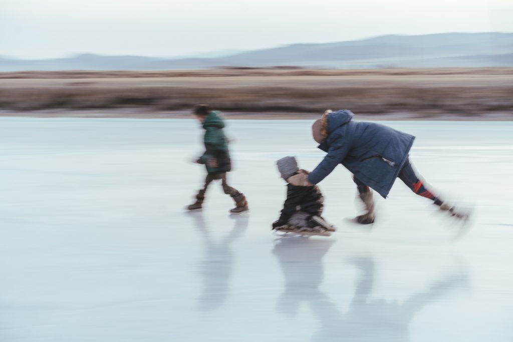 Mongolian kids playing on their home-made ice skates across the frozen river. Captured by adventure photographer stefan Haworth