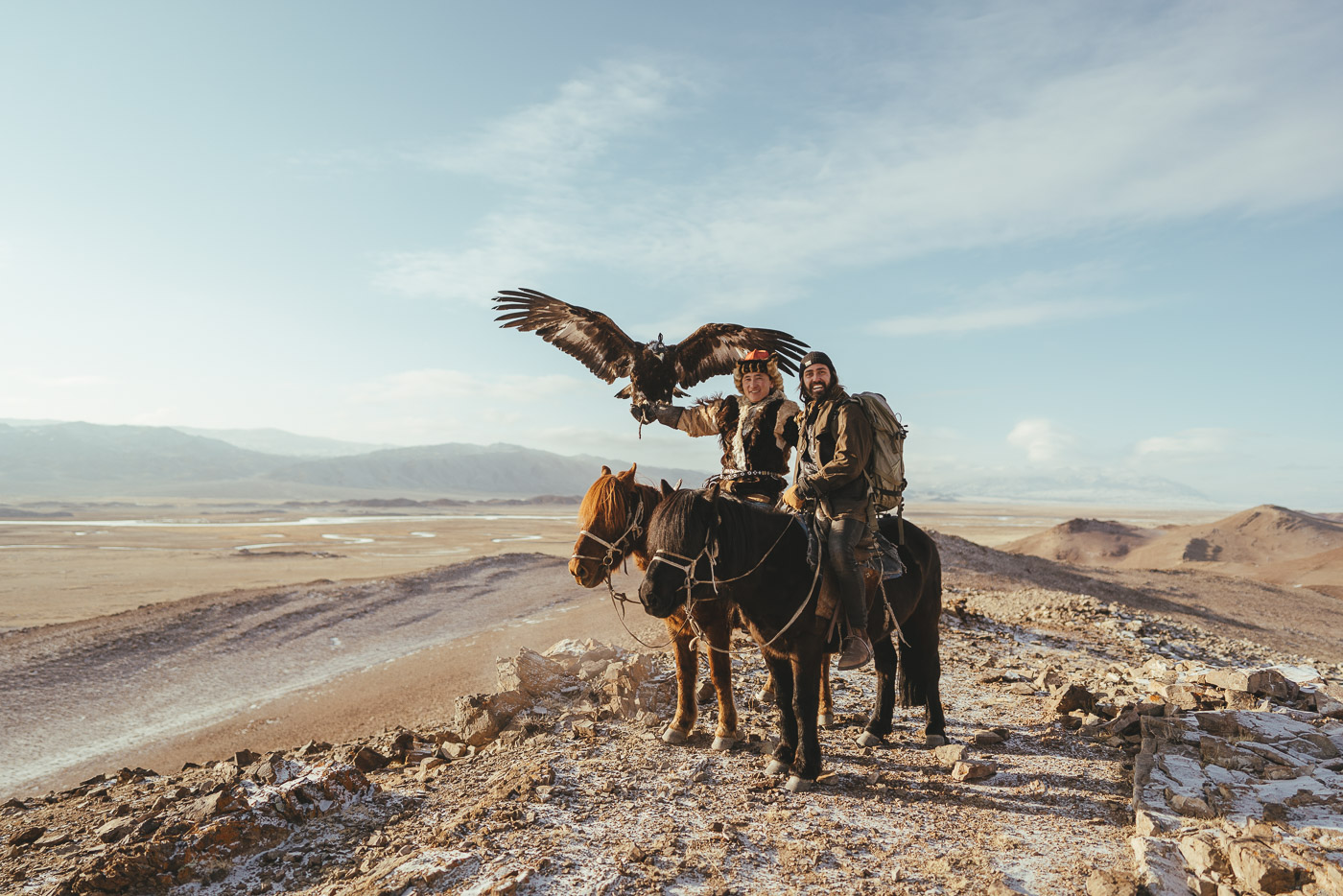 Adventure photographer Stefan Haworth and Kazakh eagle Hunter holding eagle on horseback in the western Mongolian Mountains.