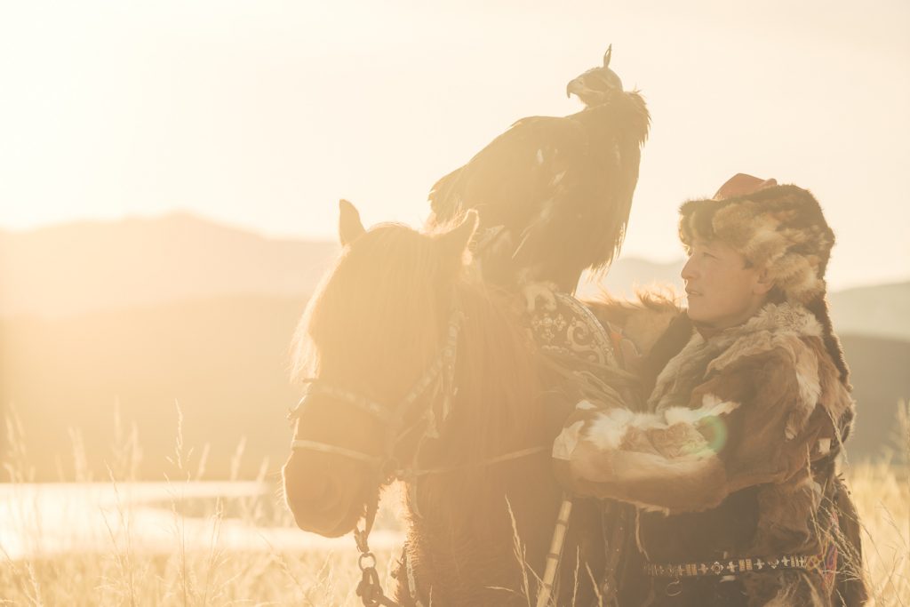 Kazakh Eagle Hunter on horseback in golden light in the mountains of western Mongolia. Captured by adventure photographer Stefan Haworth