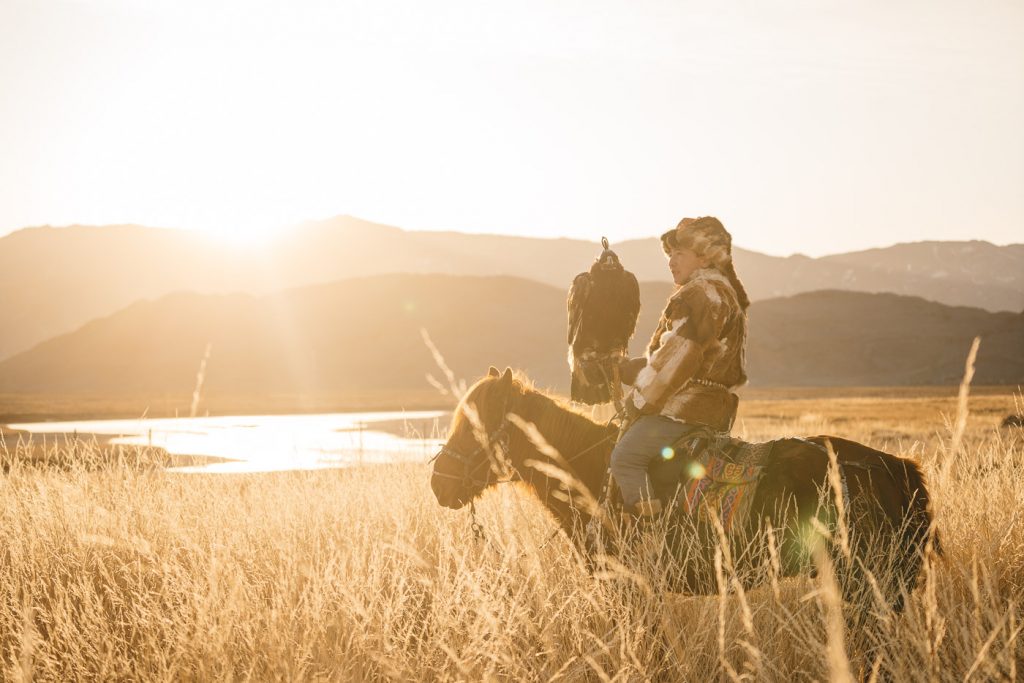 Kazakh Eagle Hunter on horseback in golden light in the mountains of western Mongolia. Captured by adventure photographer Stefan Haworth