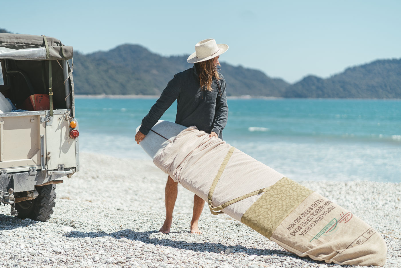 Photographer Stefan Haworth taking out the Longboard on the Jackson Bay beach on the West Coast of the South Island of New Zealand