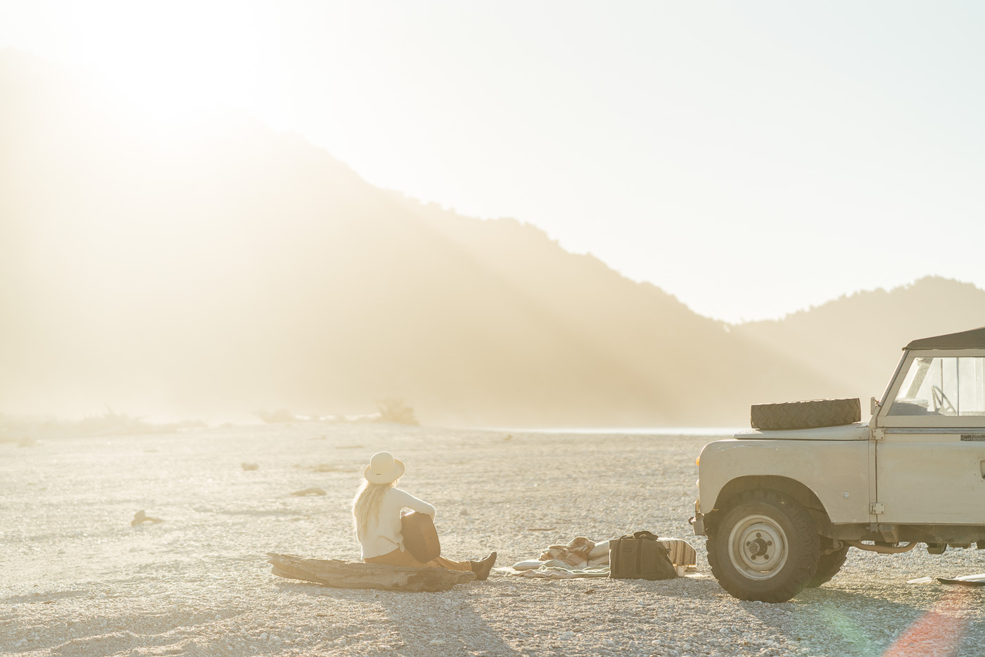 Jade Barclay playing guitar at sunset beside the Series Land Rover in Jackson bay on the West coast of New Zealand. Captured by Sony Ambassador and Photographer Stefan Haworth