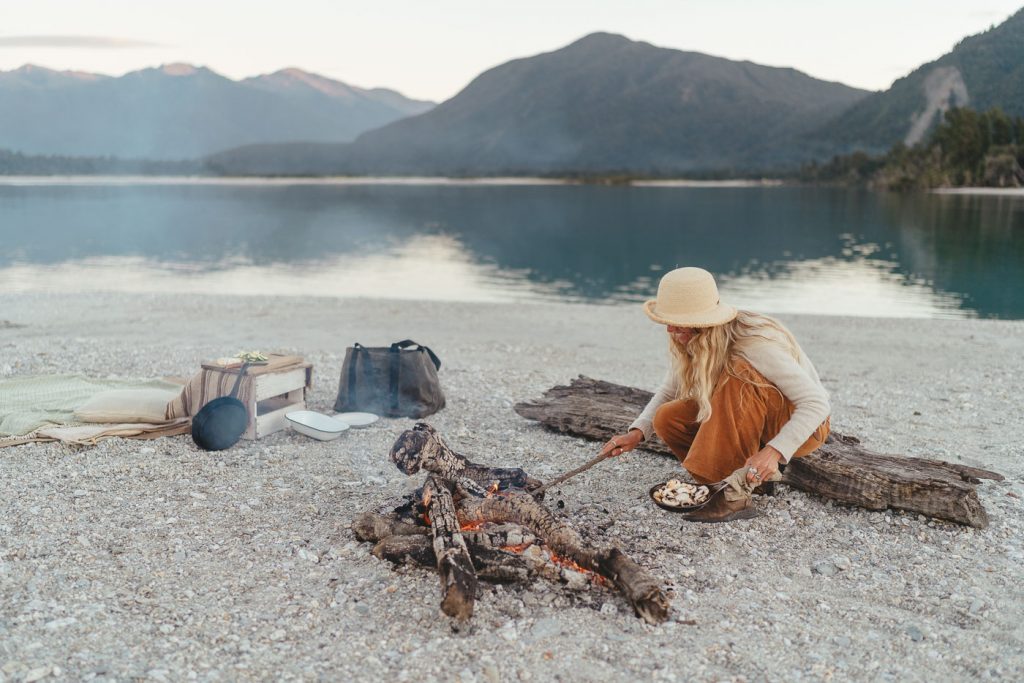 Jade Barclay cooking nachoes in a cast iron pan on the fire at Jackson bay on the west Coast of New Zealand. Captured by Sony Ambassador and Photographer Stefan Haworth