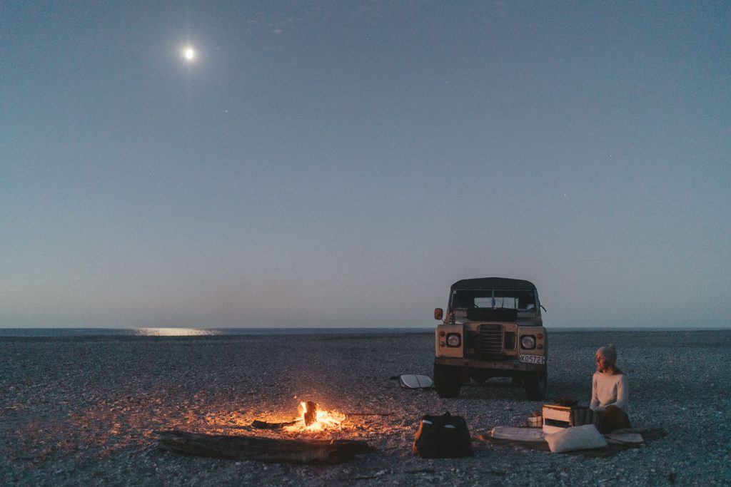 Jade Barclay enjoying a Campfire under the full moon beside the Series Land Rover in Jackson bay on the West coast of New Zealand. Captured by Sony Ambassador and Photographer Stefan Haworth