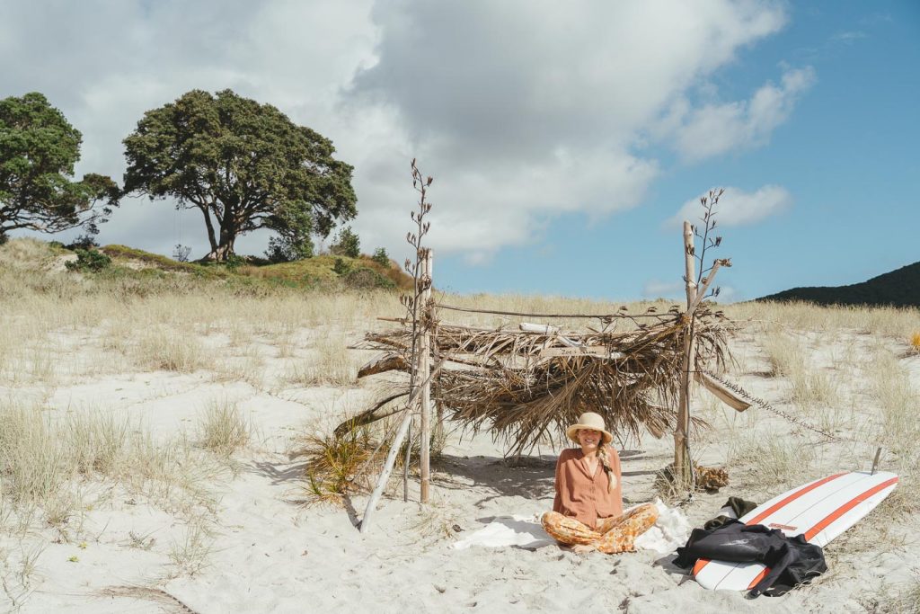 Jade Barclay relaxing on the white sand beach of great Barrier Island