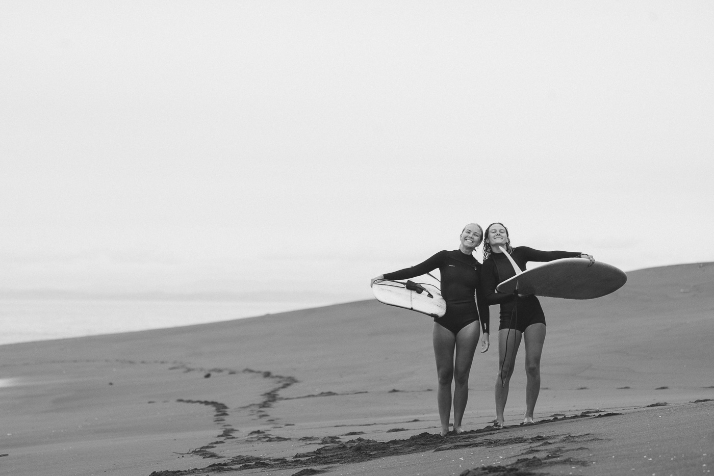 Moa Raud and Karin Falk in wetsuits after a surf at Mahia on the East Cape road trip of New Zealand. Captured by Adventure photographer Stefan Haworth