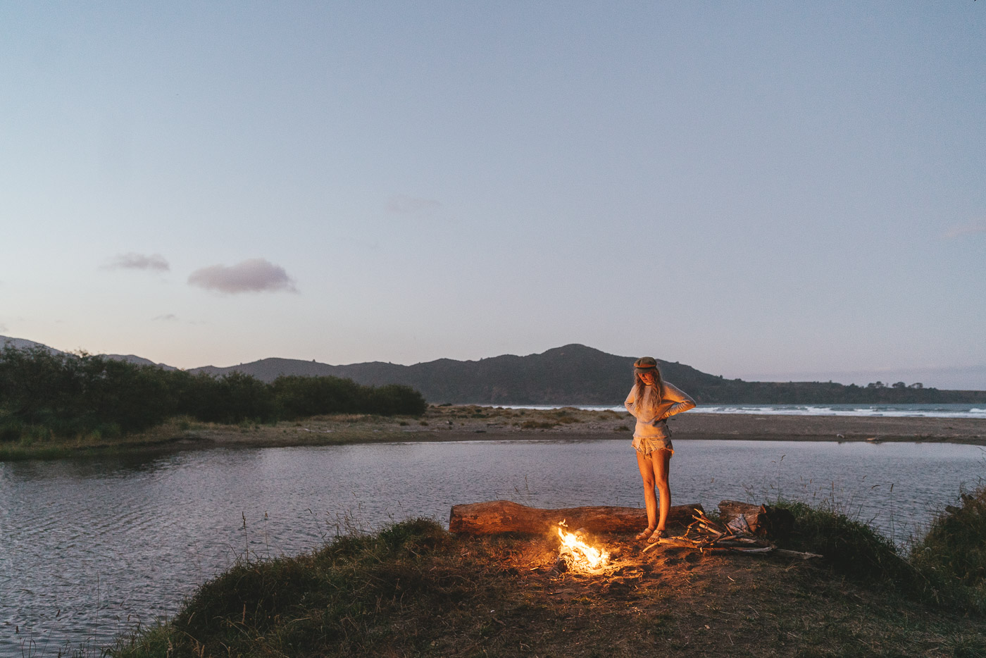 Beach campfire with Jade Barclay at sunset on the East Cape road trip of New Zealand. Captured by Adventure photographer Stefan Haworth