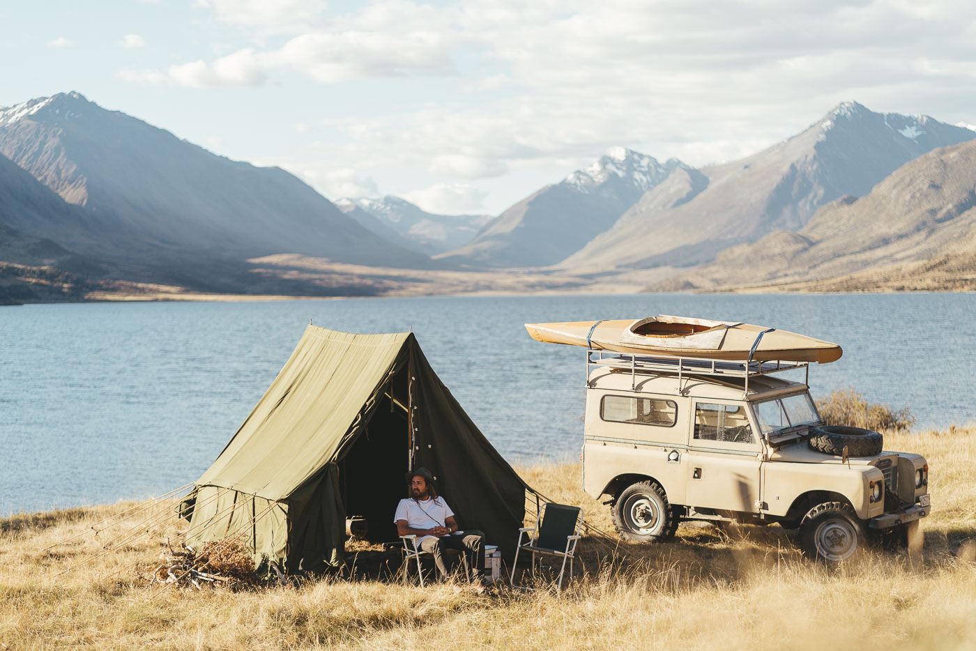 Adventure Photographer Stefan Haworth camping in canvas tent and Land rover Series at a remote lake in the Southern Alps.