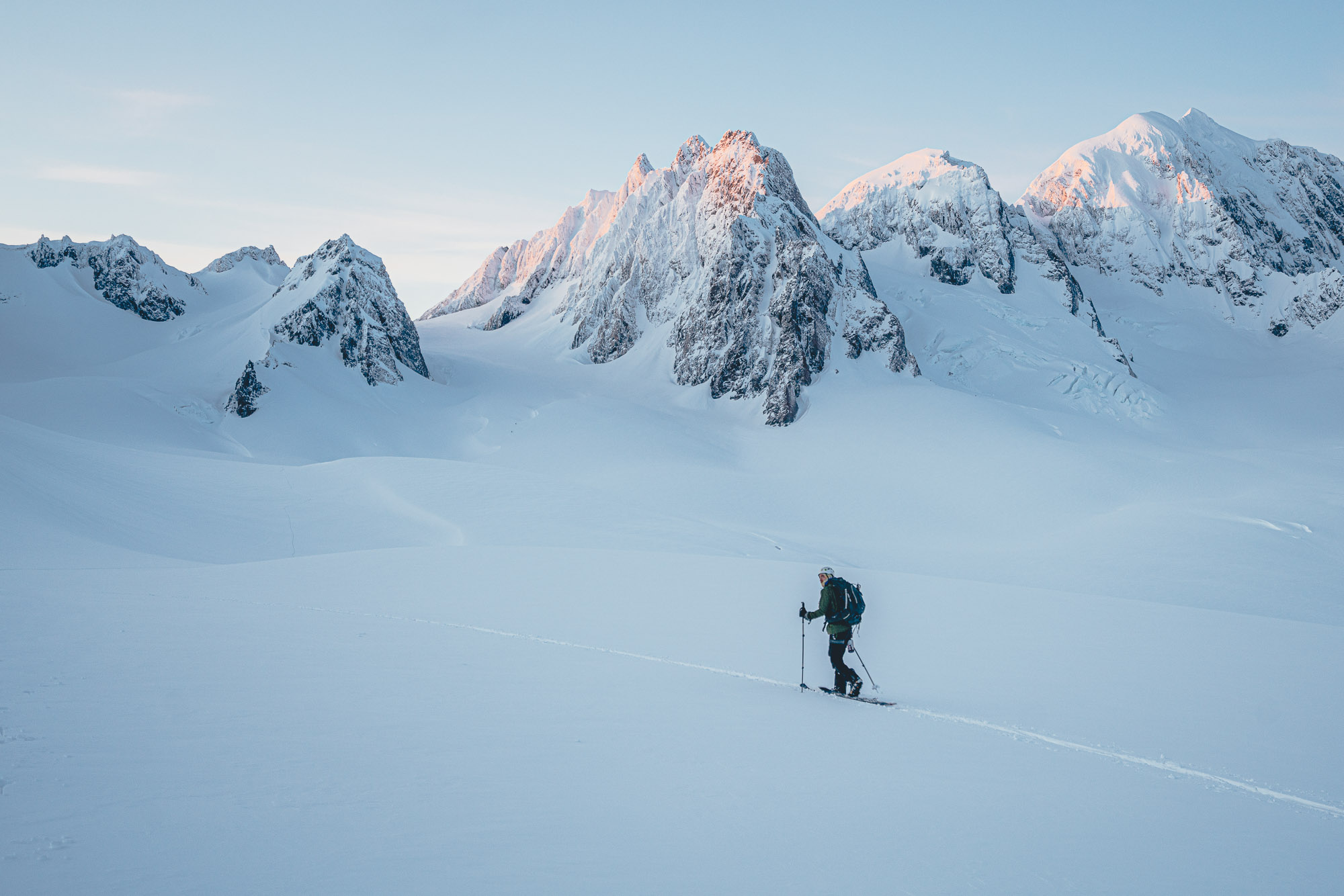 Backcountry snowboarder on the fox glacier with mount Tasman in the background during sunrise, New Zealand