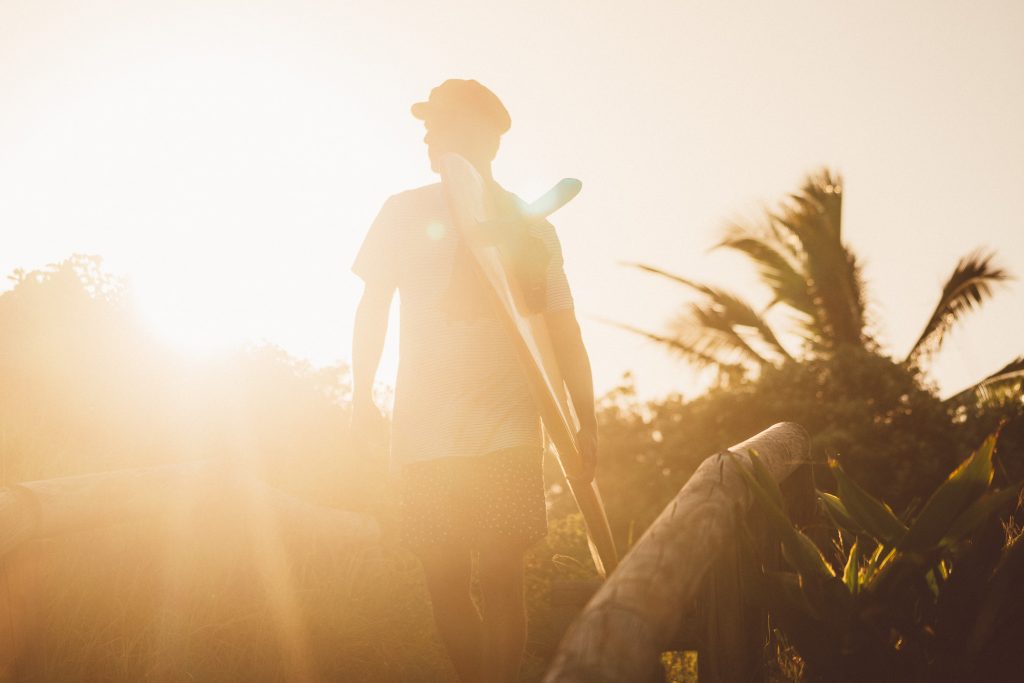 Surfer walking to the beach with surfboard and palm trees, noosa Australia