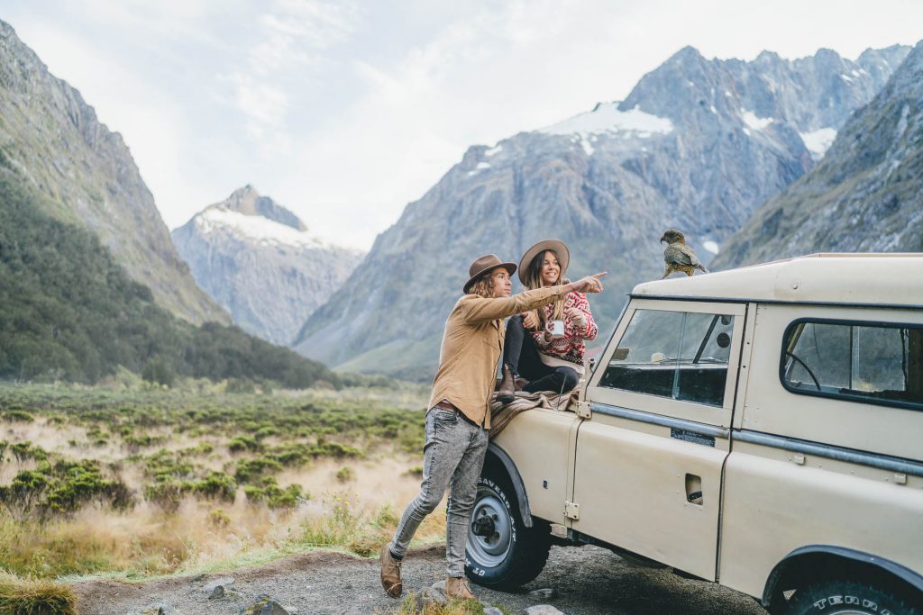 Neri and Manu from Ottway the label playing with Kea on Land Rover in Fiorldland on Milford Sound Road for Will and Bear NZ Road trip photoshoot